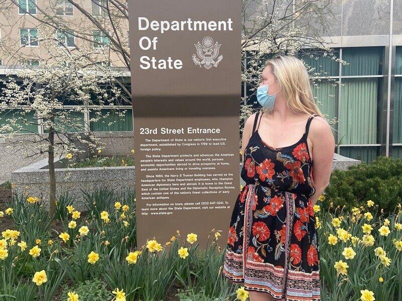 woman standing in front of a department of state sign